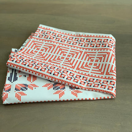 Two patterned fabric swatches stacked on a wooden surface